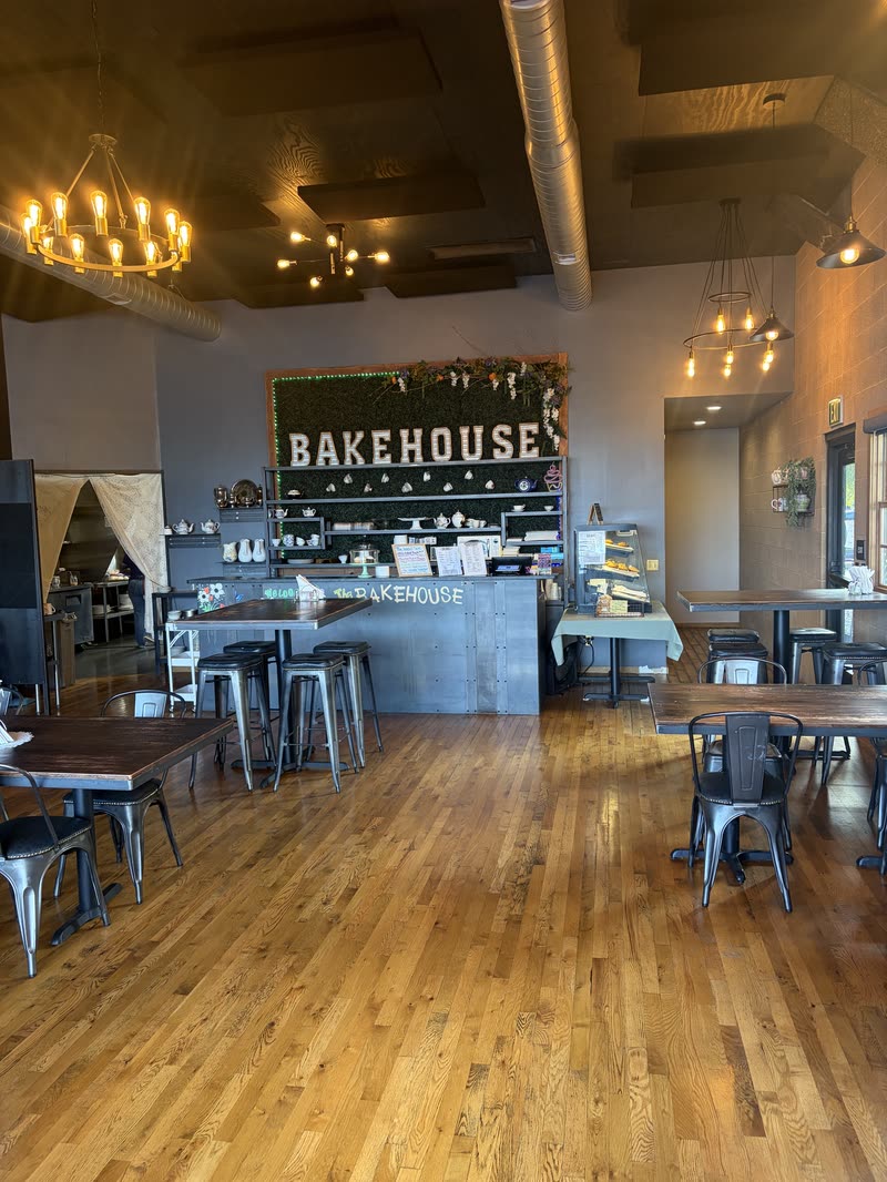 The dining room on a sunny morning: chandeliers, wood floors, tables and stools, and the BAKEHOUSE wall at the back